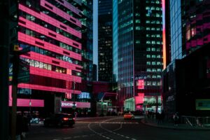 Vibrant city street at night with pink lights.