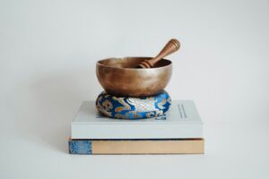 Singing bowl and mallet rest on books.