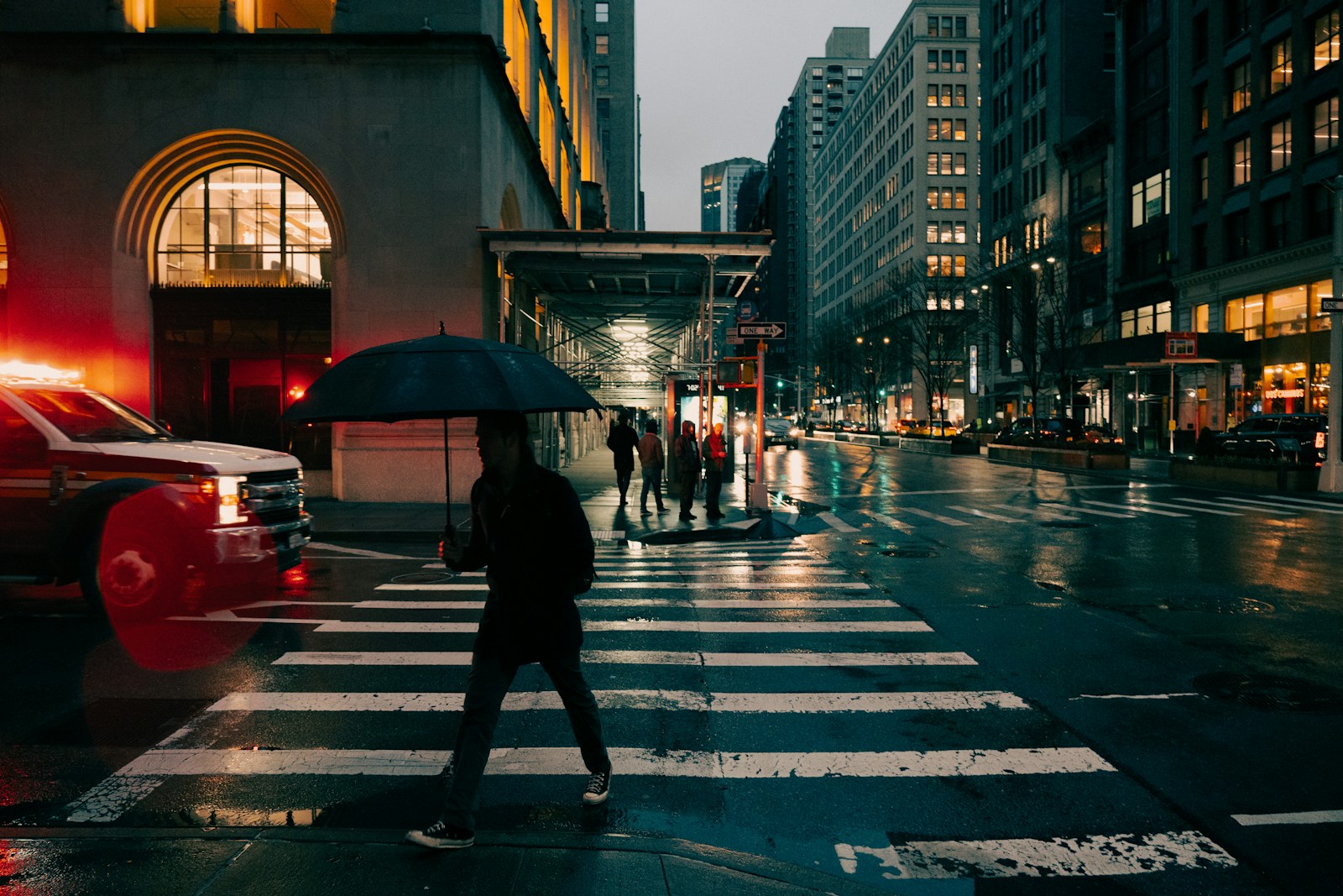 A person crosses a wet street in the city.