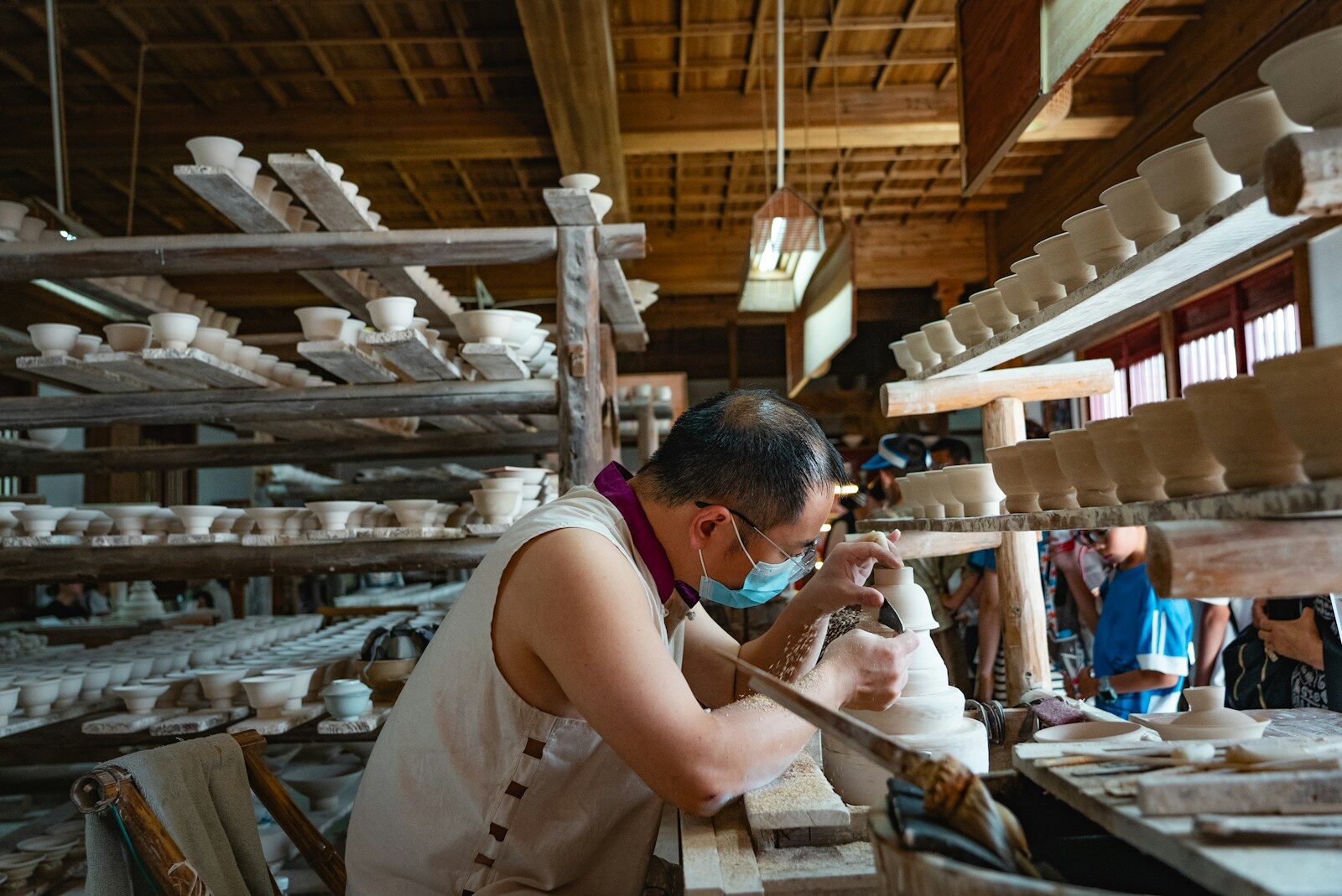 Potter shaping clay on a wheel in a workshop.